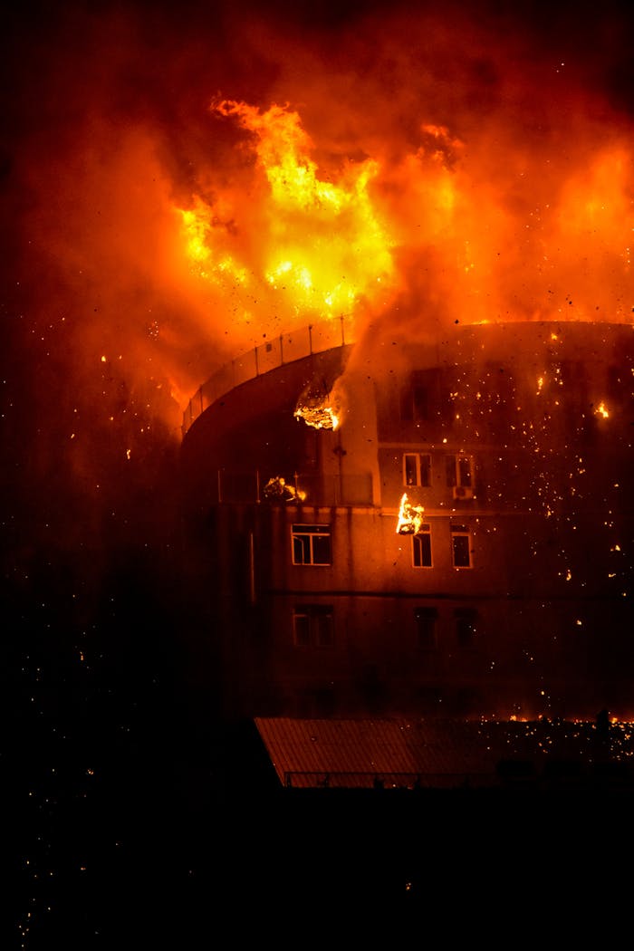 A building dramatically on fire at night, showcasing intense flames and smoke.
